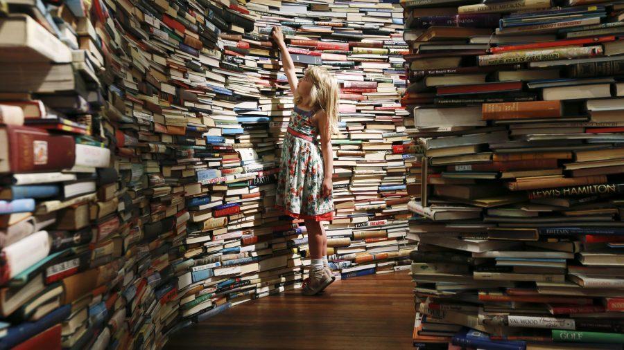 Leona, 7, poses inside a labyrinth installation made up of 250,000 books titled aMAZEme by Marcos Saboya and Gualter Pupo at the Royal Festival Hall in central London July 31, 2012. REUTERS/Olivia Harris (BRITAIN - Tags: ENTERTAINMENT TPX IMAGES OF THE DAY) - RTR35PZS